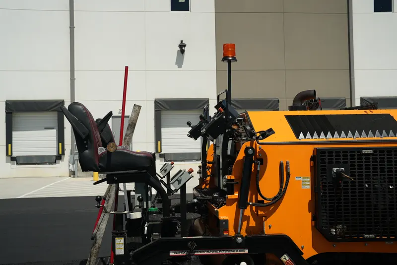 Close-up of the orange paving machine at a warehouse parking lot job