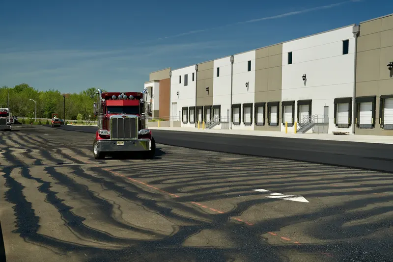 Wide view of a newly paved parking lot with a dump truck by the warehouse docks