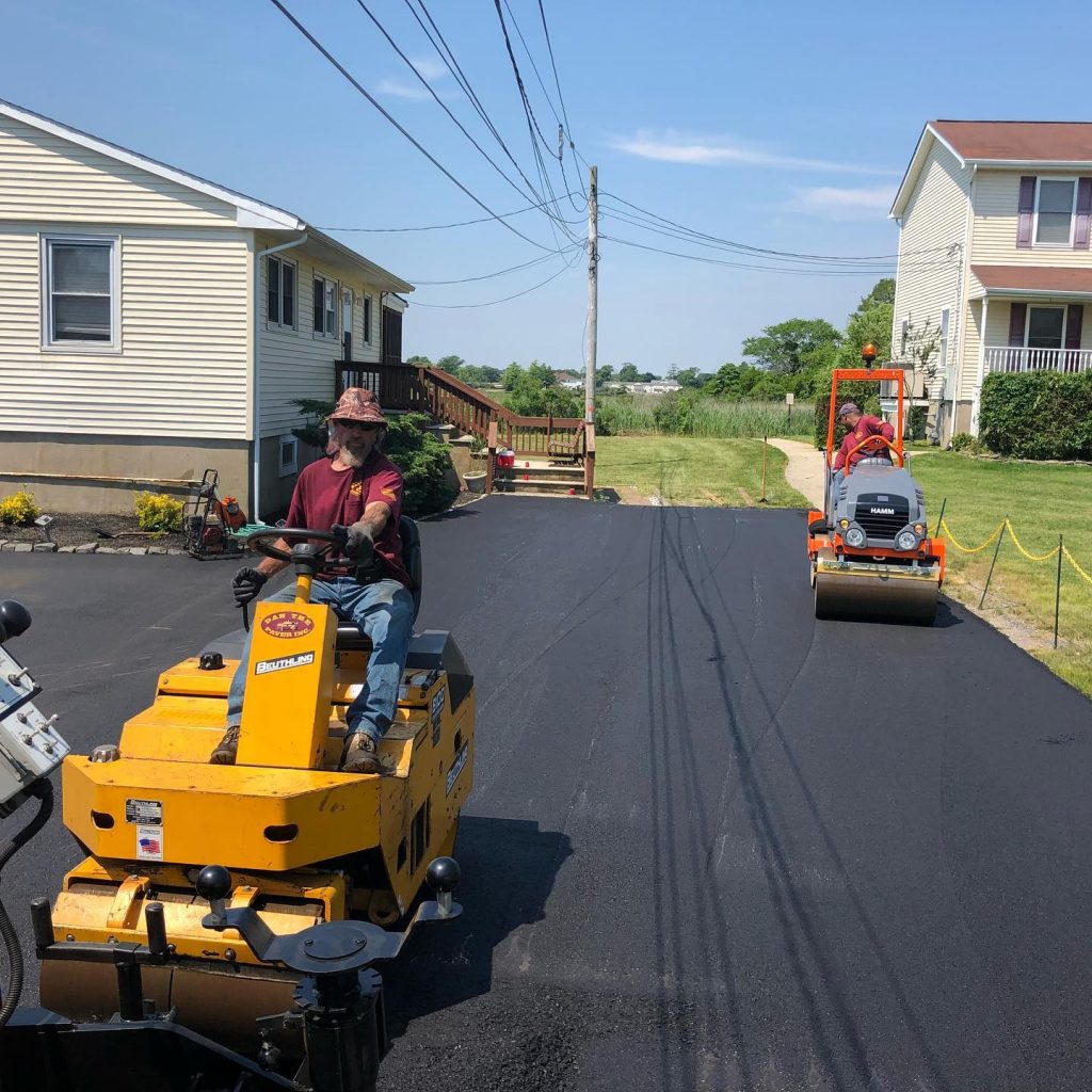 Dan the Paver worker operating paving machine on asphalt driveway project.